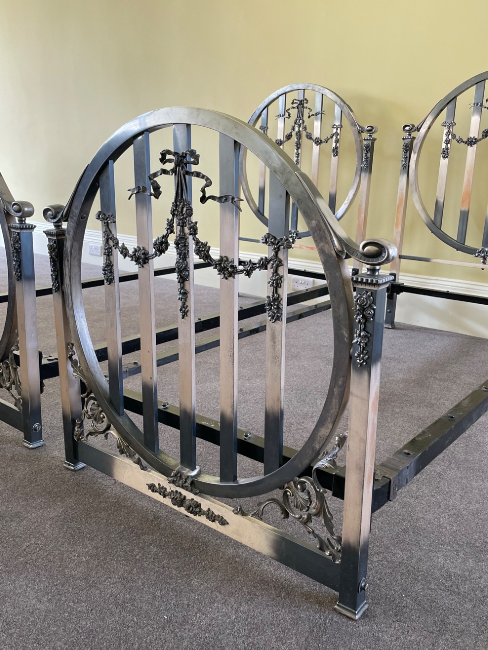 A matching pair of Art Nouveau nickel-plated single bed frames with circular slatted panels and cast ribbon swags. View II
