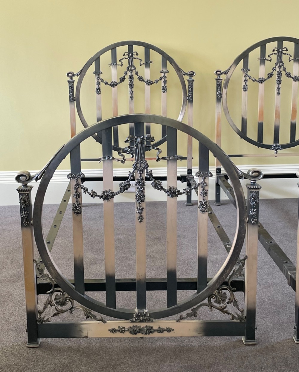 A matching pair of Art Nouveau nickel-plated single bed frames with circular slatted panels and cast ribbon swags. View IV
