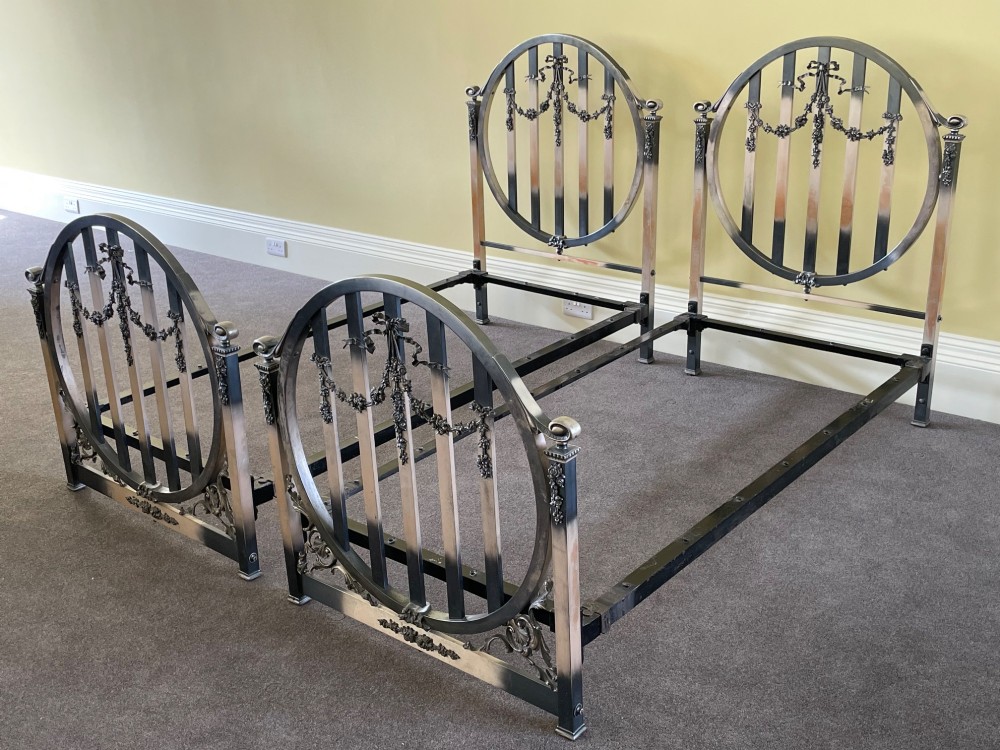 A matching pair of Art Nouveau nickel-plated single bed frames with circular slatted panels and cast ribbon swags. View V