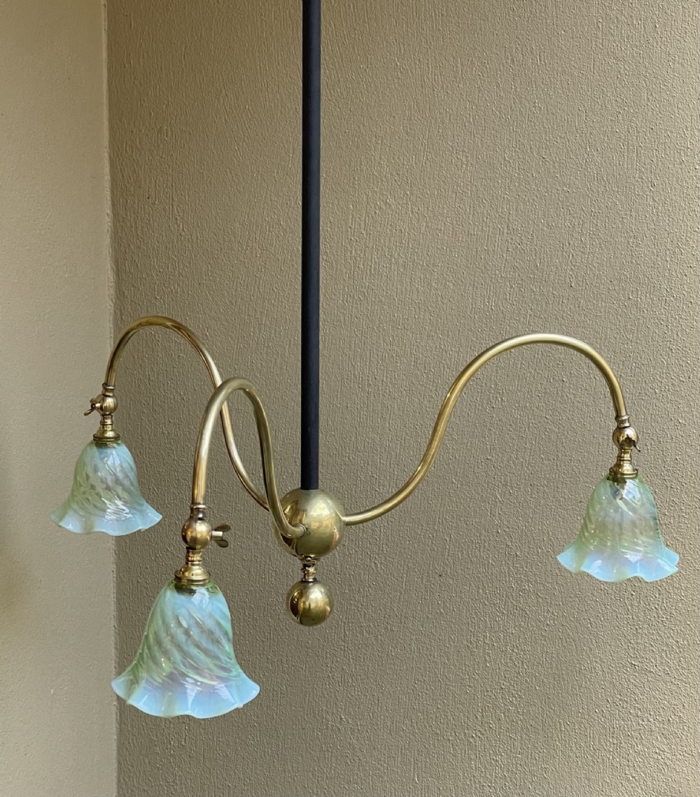 An Arts and Crafts style brass three-arm ceiling light featuring downward-curving swan-neck arms holding fluted opalescent green glass shades suspended from a central stem. View II