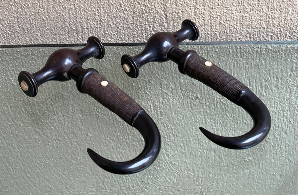 A pair of Victorian boot pulls featuring turned dark handles with bone inlays and curved horn hooks.