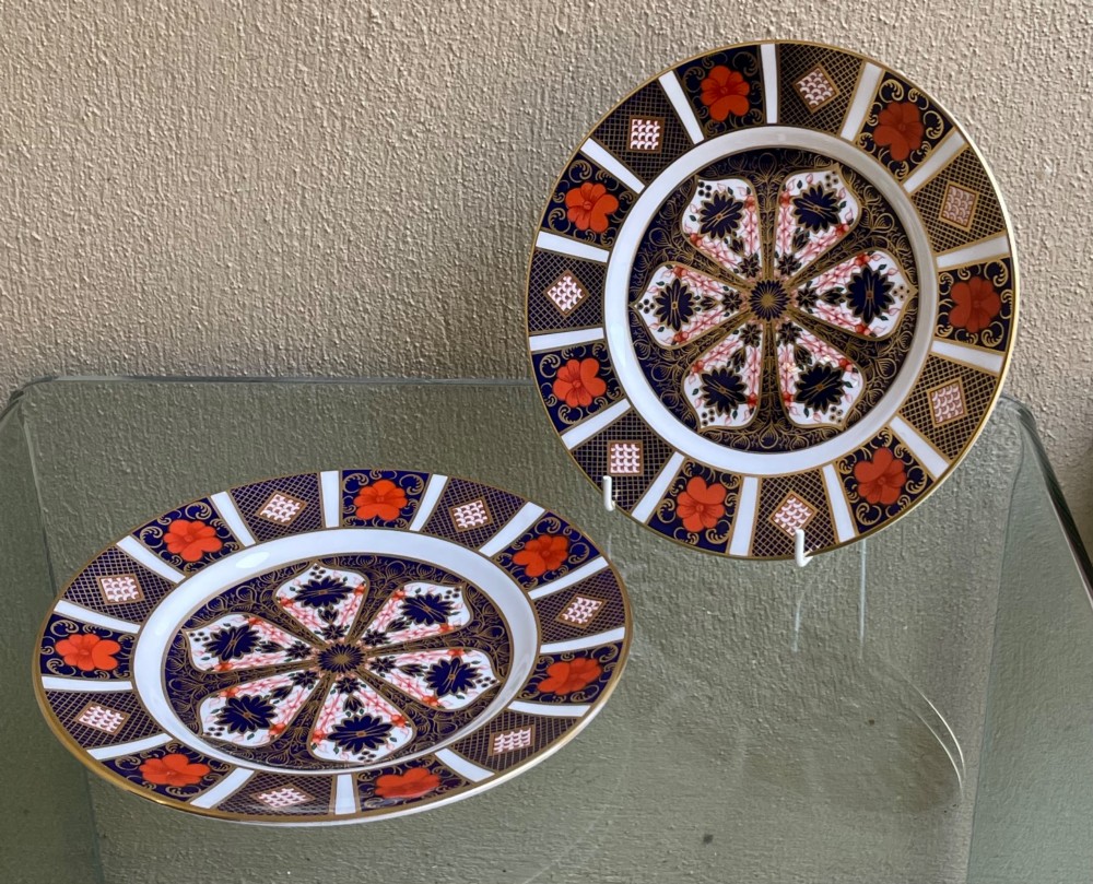 A pair of circular fine bone china plates decorated in an intricate Imari pattern with cobalt blue, iron red floral motifs, and detailed gold gilding.