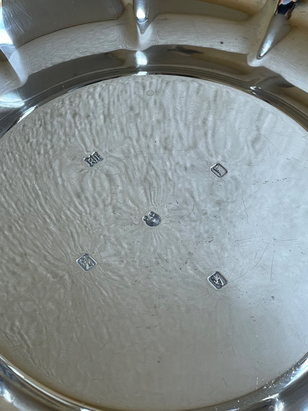 A circular solid silver strawberry dish featuring fluted lobed edges and hallmarks stamped in the flat central well. View IV