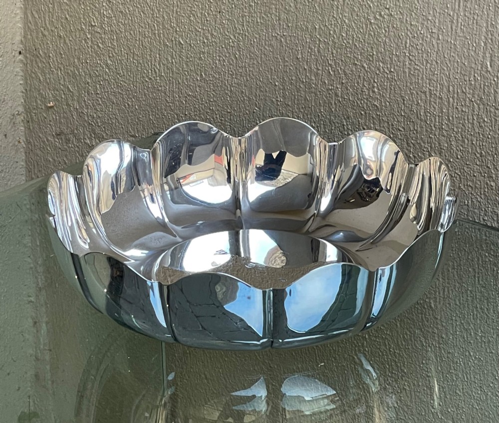 A circular solid silver strawberry dish featuring fluted lobed edges and hallmarks stamped in the flat central well. View VI