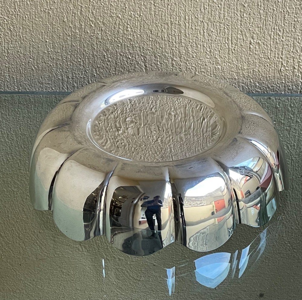A circular solid silver strawberry dish featuring fluted lobed edges and hallmarks stamped in the flat central well. View VII