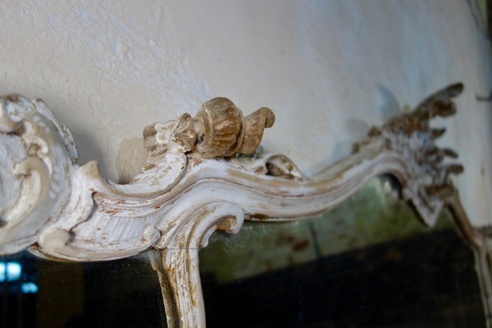 An expansive 19th-century French Rococo wall mirror featuring a carved off-white serpentine frame decorated with ornate acanthus scrolls and cresting. View IV