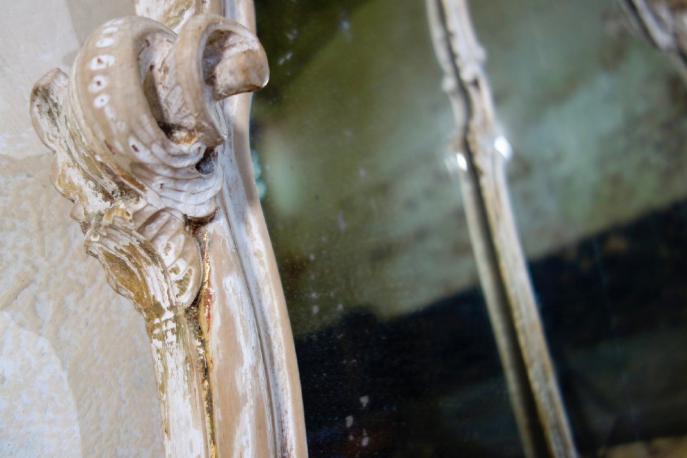An expansive 19th-century French Rococo wall mirror featuring a carved off-white serpentine frame decorated with ornate acanthus scrolls and cresting. View V