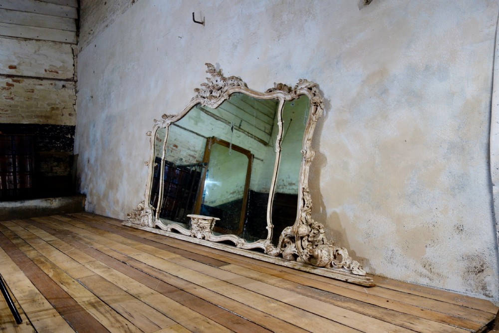 An expansive 19th-century French Rococo wall mirror featuring a carved off-white serpentine frame decorated with ornate acanthus scrolls and cresting. View X
