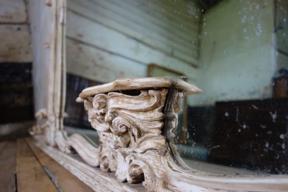 An expansive 19th-century French Rococo wall mirror featuring a carved off-white serpentine frame decorated with ornate acanthus scrolls and cresting. View XVIII