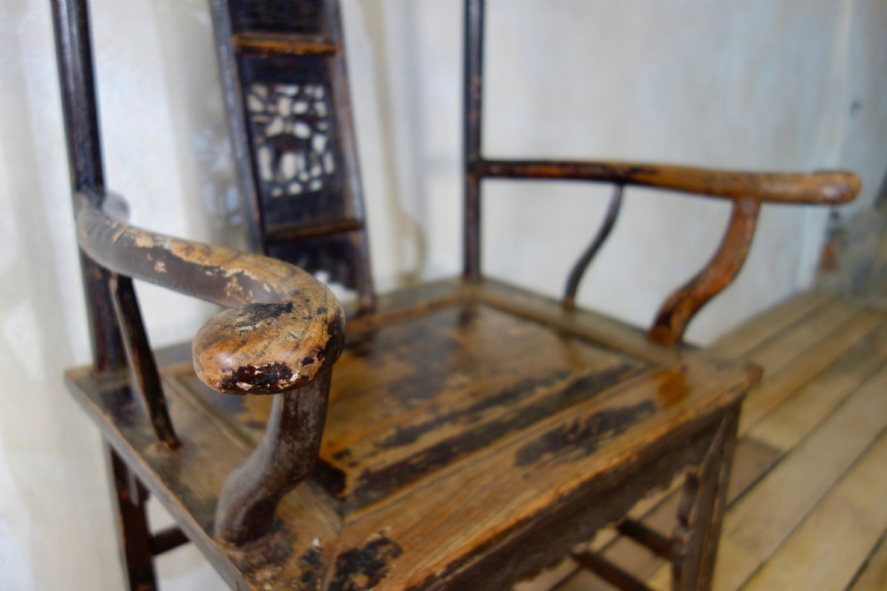 A 19th-century dark elm Chinese officials hat armchair featuring a carved yoke-back crest rail and pierced splat. View IV