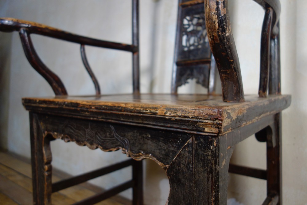 A 19th-century dark elm Chinese officials hat armchair featuring a carved yoke-back crest rail and pierced splat. View V