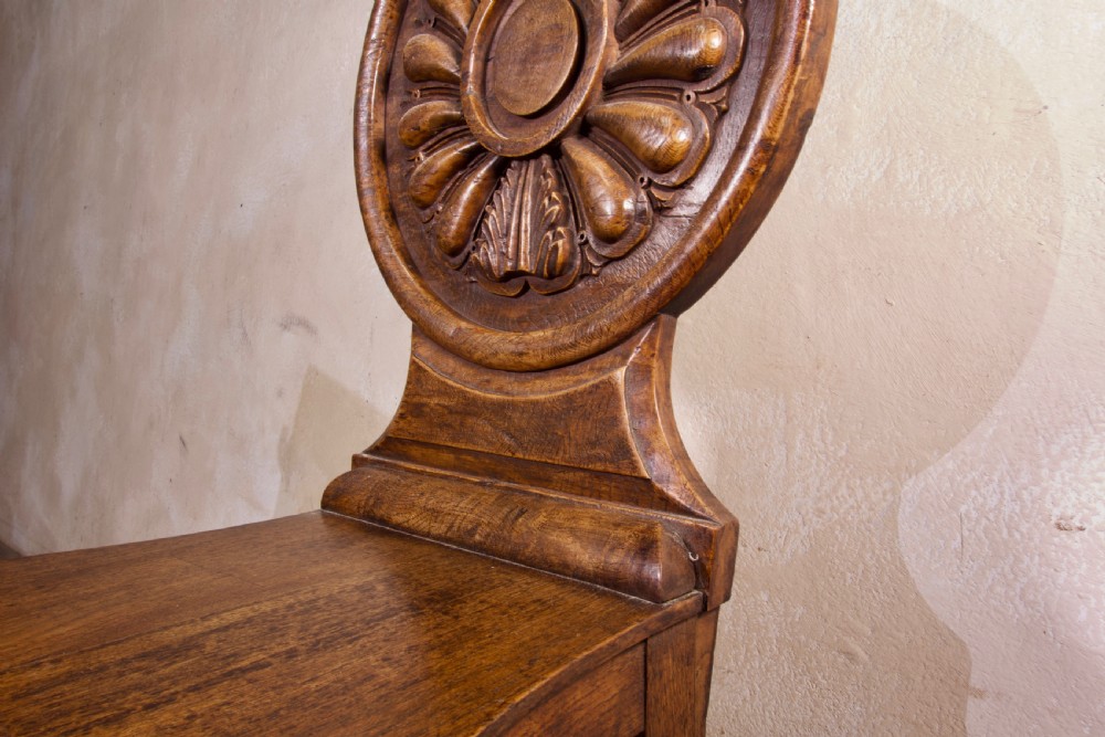 A 19th-century William IV hall chair made from elm and burr elm featuring a carved circular medallion back, solid wooden seat, turned front legs, and curved rear legs. View II