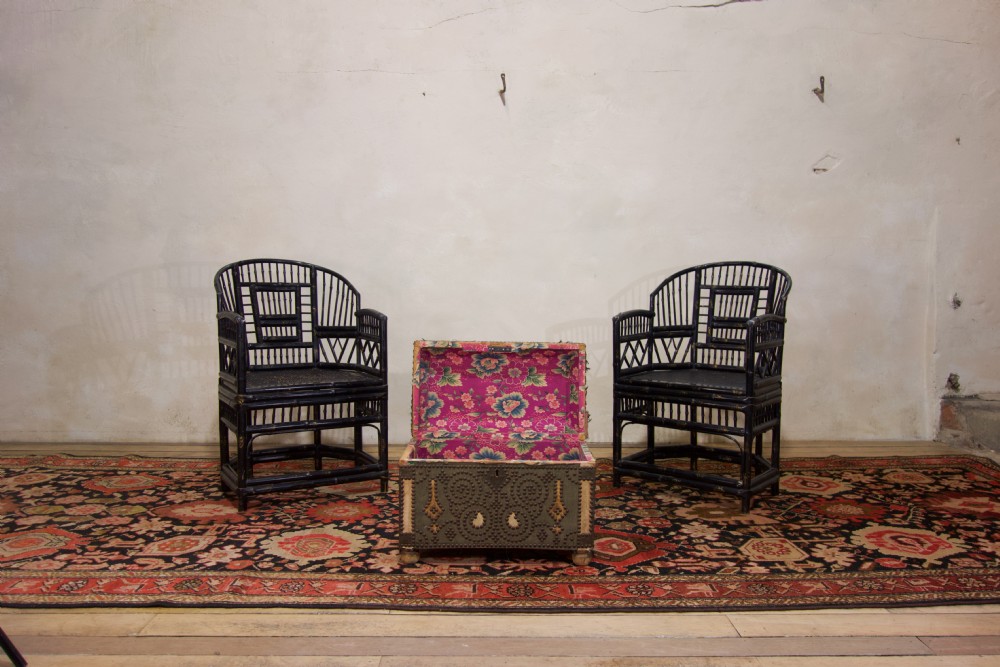 A small 19th-century French trunk featuring olive green fabric, brass stud patterning, iron side handles, and wooden bun feet. View VI