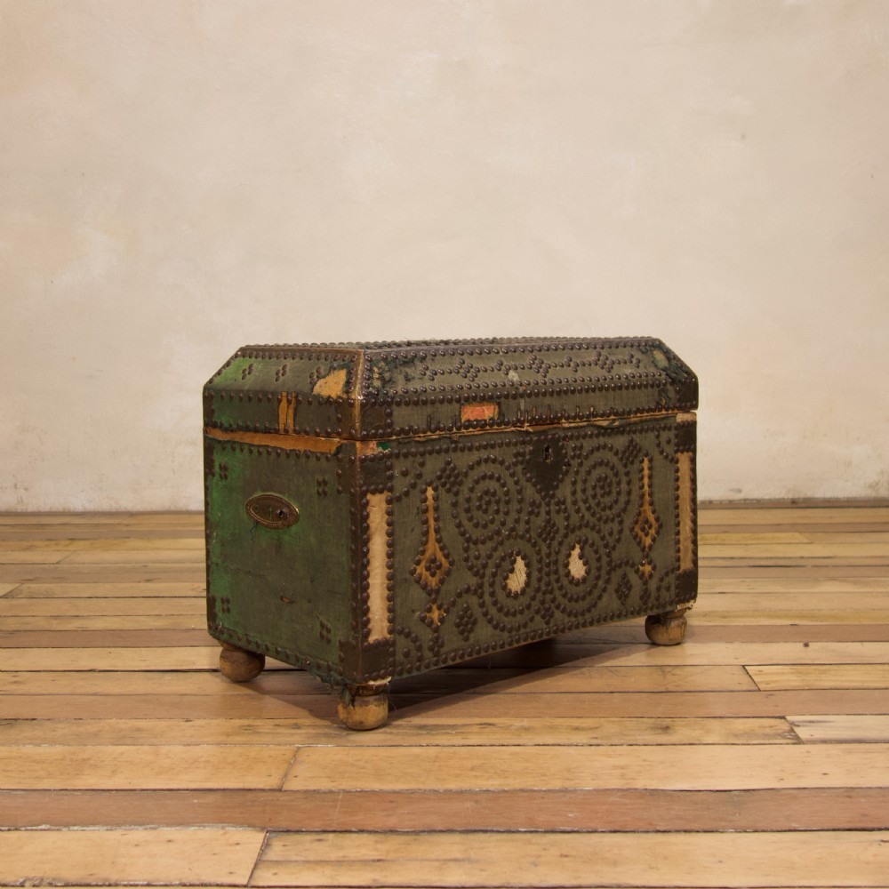 A small 19th-century French trunk featuring olive green fabric, brass stud patterning, iron side handles, and wooden bun feet. View XI