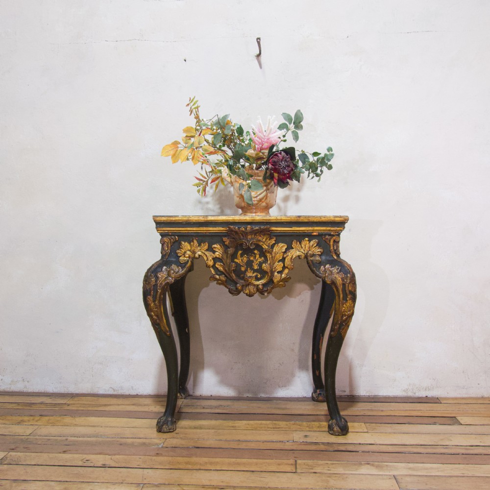 An 18th-century Italian Baroque console table featuring a marble top, a dark painted frame with gilded acanthus leaf carvings, and cabriole legs.