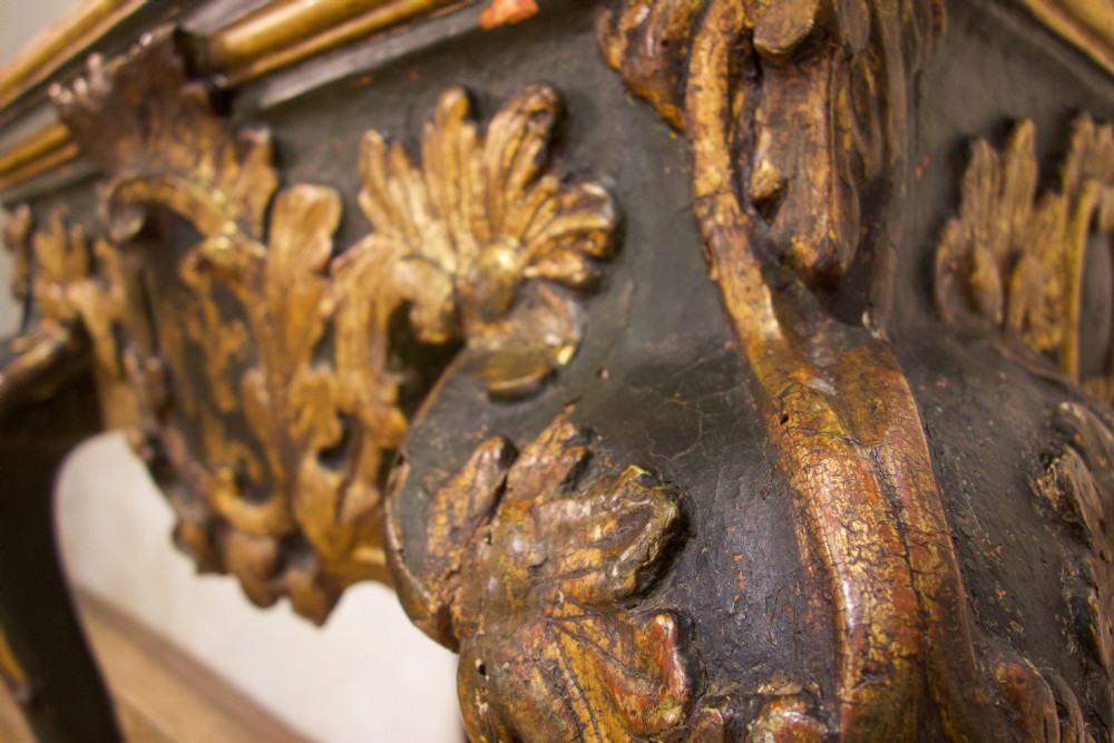 An 18th-century Italian Baroque console table featuring a marble top, a dark painted frame with gilded acanthus leaf carvings, and cabriole legs. View V