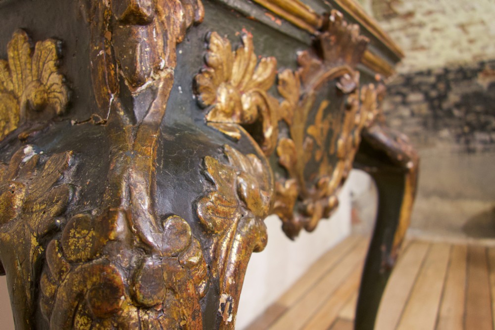 An 18th-century Italian Baroque console table featuring a marble top, a dark painted frame with gilded acanthus leaf carvings, and cabriole legs. View VII