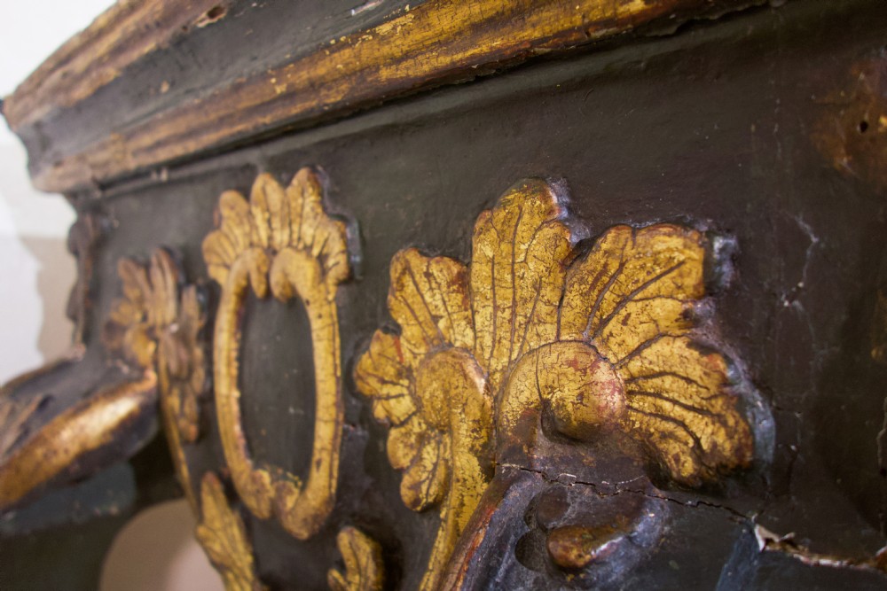 An 18th-century Italian Baroque console table featuring a marble top, a dark painted frame with gilded acanthus leaf carvings, and cabriole legs. View IX