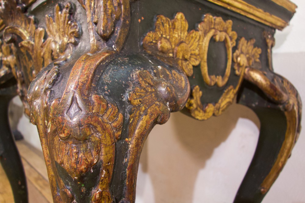 An 18th-century Italian Baroque console table featuring a marble top, a dark painted frame with gilded acanthus leaf carvings, and cabriole legs. View XV