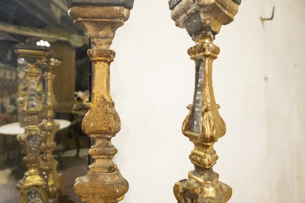 A pair of tall 18th-century Venetian giltwood altar candlesticks featuring carved details, inset mirrored glass panels, and triform bases. View II
