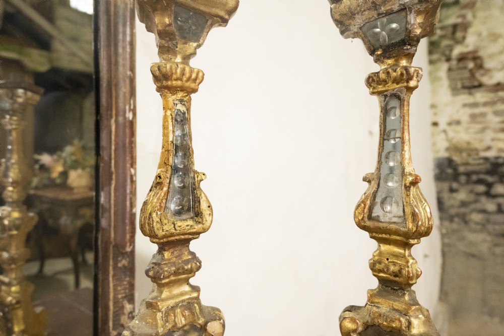 A pair of tall 18th-century Venetian giltwood altar candlesticks featuring carved details, inset mirrored glass panels, and triform bases. View IV
