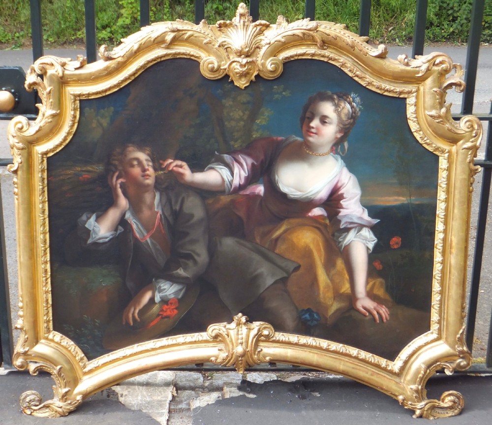 An 18th-century style French Rococo oil painting on canvas depicting a pastoral scene within an elaborate carved gold gilt frame.
