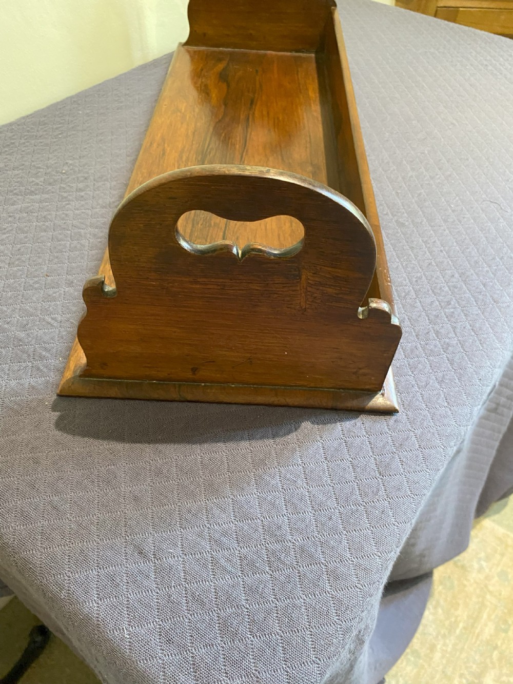A mid-19th-century dark rosewood tabletop book rack featuring open cut-out side handles and a flat rectangular base. View III