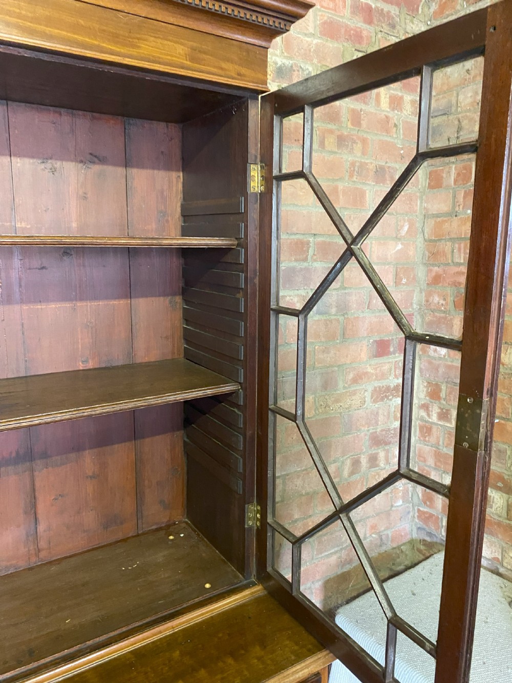 A George III mahogany secretaire bookcase featuring an upper glazed cabinet with geometric astragal bars, positioned above a lower chest of drawers with round brass handles on bracket feet. View VI