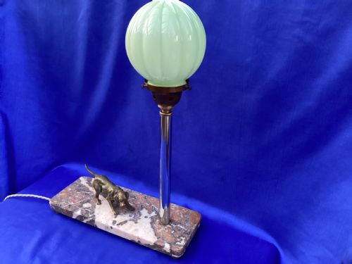 fig 1. An Art Deco French table lamp featuring a cast brass hound figure mounted on a rectangular veined marble base beside a stem supporting a pale green globe shade.
