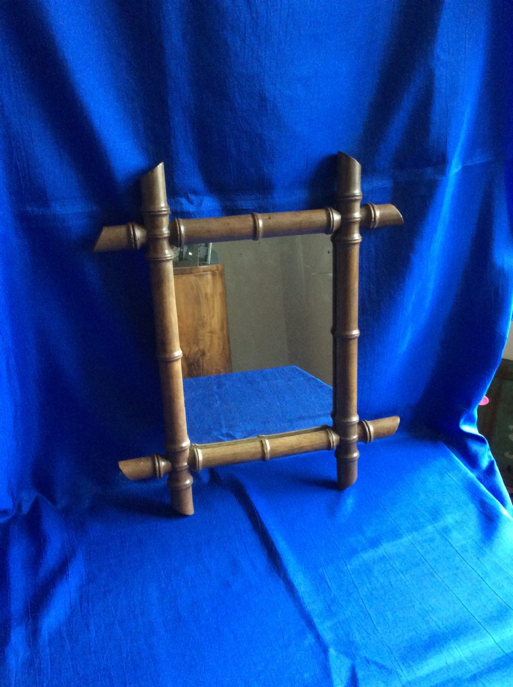 A small rectangular wall mirror surrounded by a carved timber frame crafted to resemble natural bamboo stalks with turned nodes.