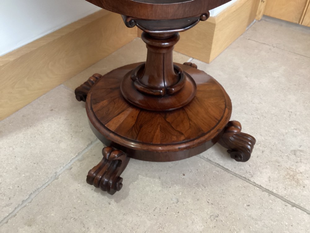 A 19th-century rosewood sewing table featuring a top drawer, a pink pleated silk work basket supported by a U-shaped frame, and a pedestal base with carved scroll feet. View XII