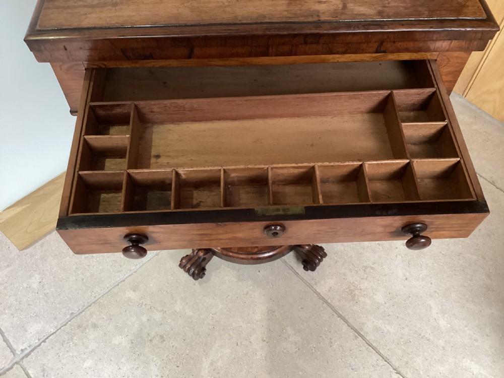 A 19th-century rosewood sewing table featuring a top drawer, a pink pleated silk work basket supported by a U-shaped frame, and a pedestal base with carved scroll feet. View XIII