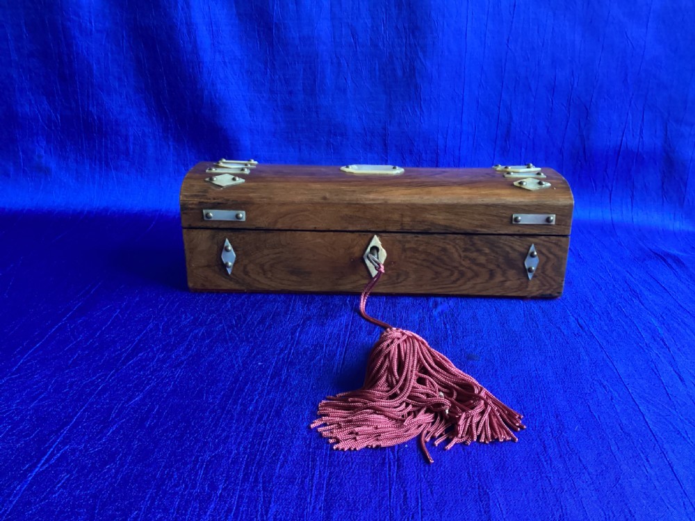A Victorian rosewood glove box featuring a domed lid, inlaid bone diamond accents, a central escutcheon, and a key with a pink tassel.