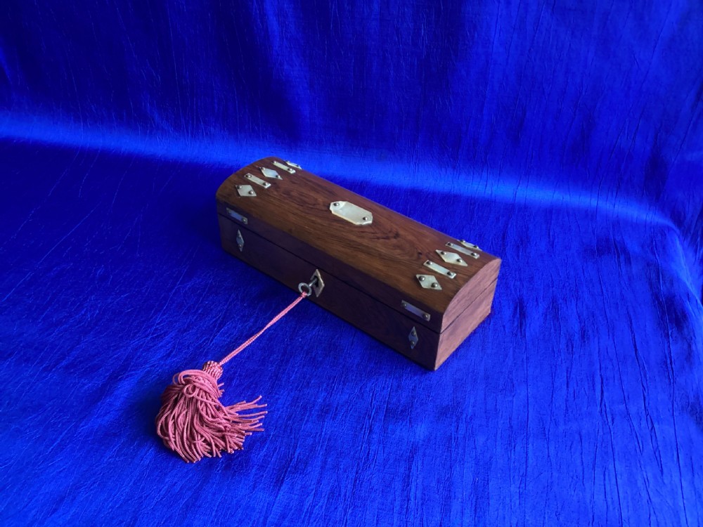 A Victorian rosewood glove box featuring a domed lid, inlaid bone diamond accents, a central escutcheon, and a key with a pink tassel. View IV