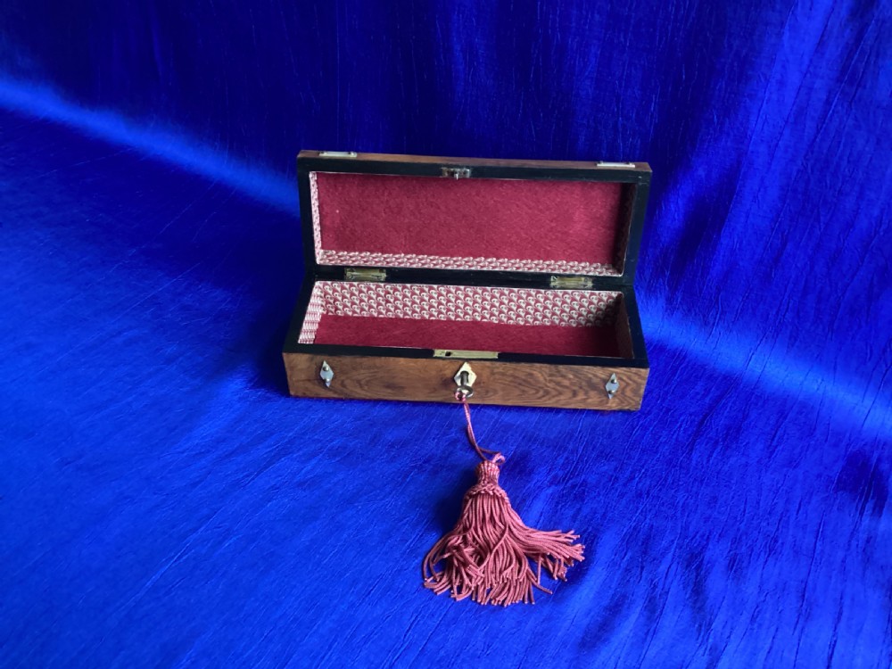 A Victorian rosewood glove box featuring a domed lid, inlaid bone diamond accents, a central escutcheon, and a key with a pink tassel. View V