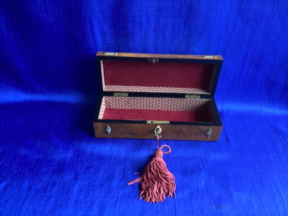 A Victorian rosewood glove box featuring a domed lid, inlaid bone diamond accents, a central escutcheon, and a key with a pink tassel. View VI