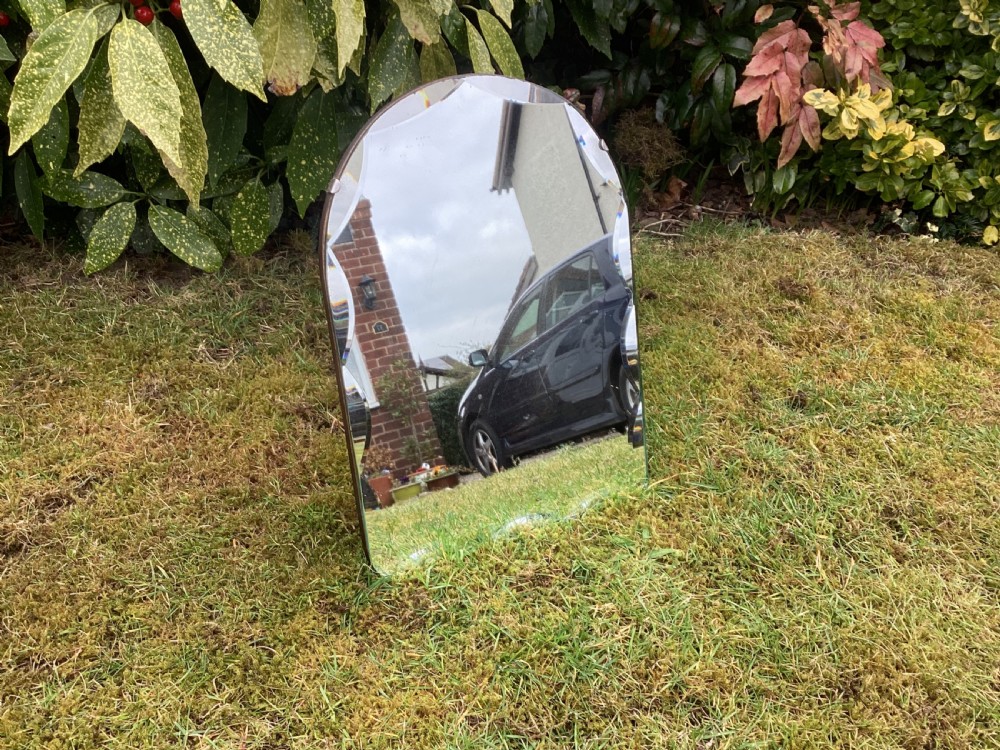 An Art Deco frameless table mirror featuring an arched top, bevelled scalloped edges, and an easel support. View V