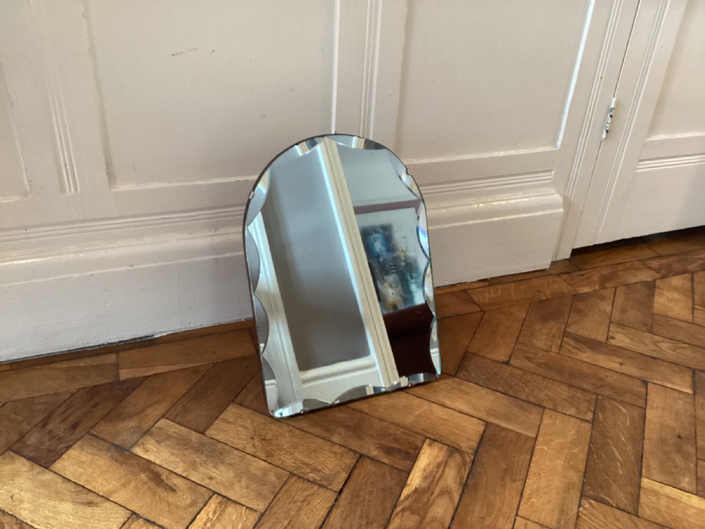 An Art Deco frameless table mirror featuring an arched top, bevelled scalloped edges, and an easel support. View VII