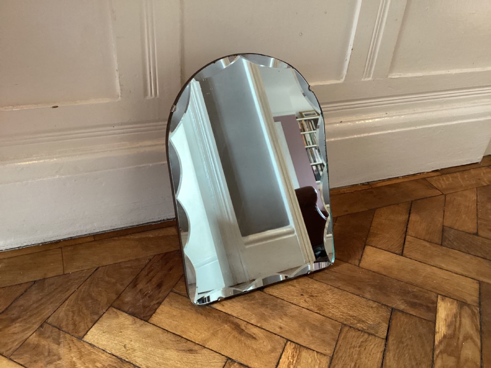 An Art Deco frameless table mirror featuring an arched top, bevelled scalloped edges, and an easel support. View VIII