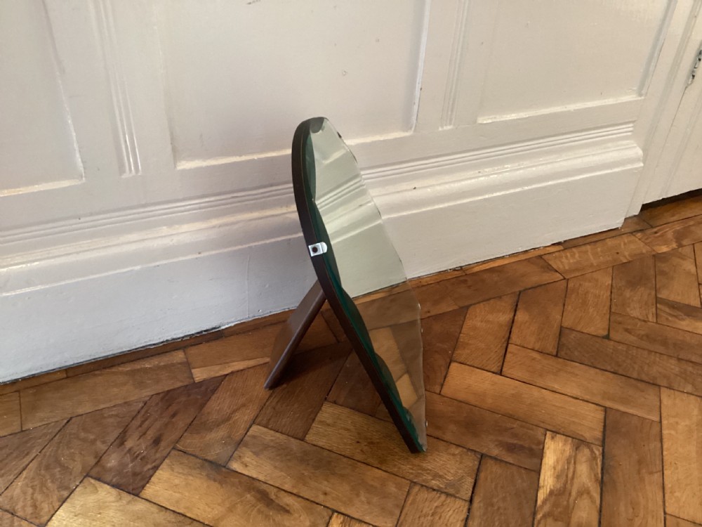 An Art Deco frameless table mirror featuring an arched top, bevelled scalloped edges, and an easel support. View IX