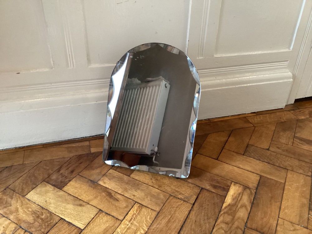 An Art Deco frameless table mirror featuring an arched top, bevelled scalloped edges, and an easel support. View X