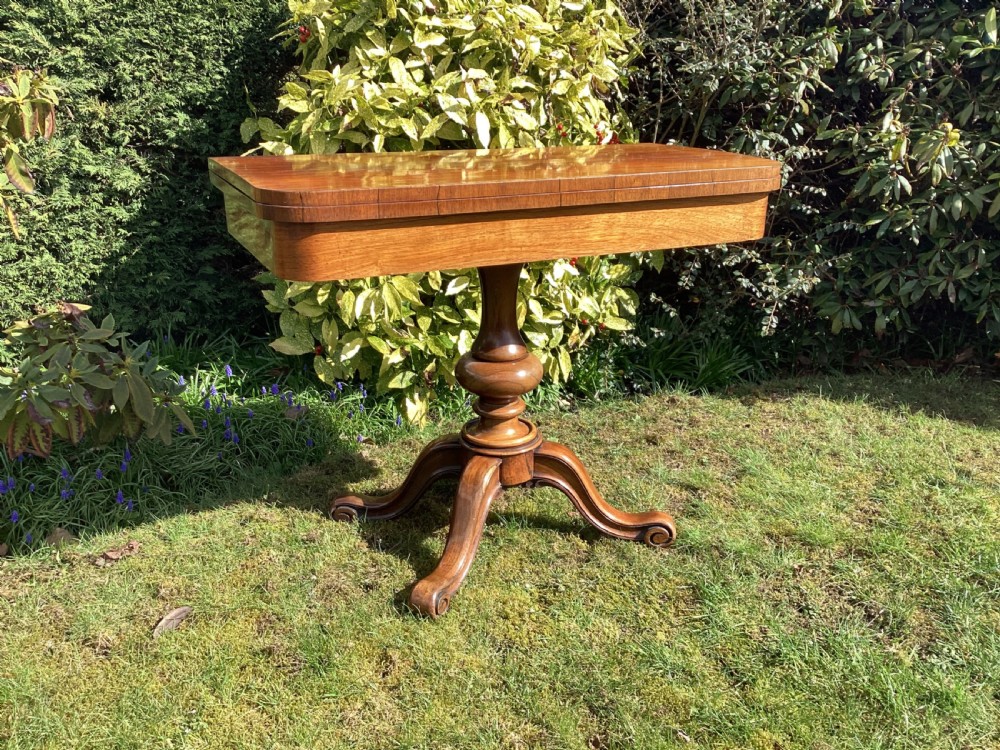 Victorian rosewood fold-over games table supported by a central turned pedestal column and four carved scroll feet. View III