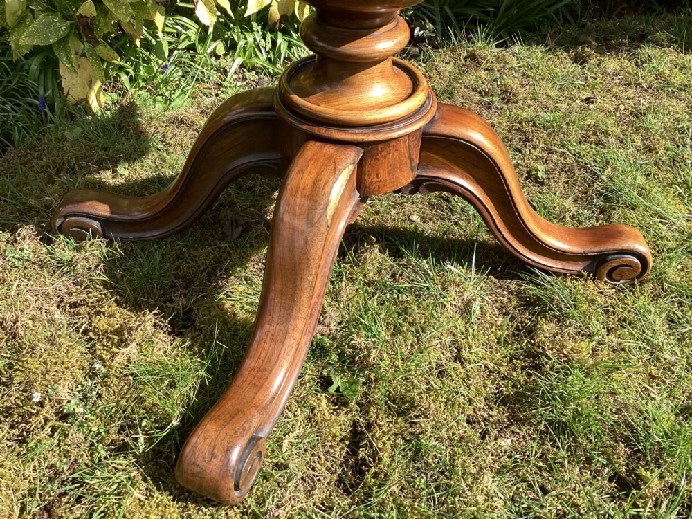 Victorian rosewood fold-over games table supported by a central turned pedestal column and four carved scroll feet. View V