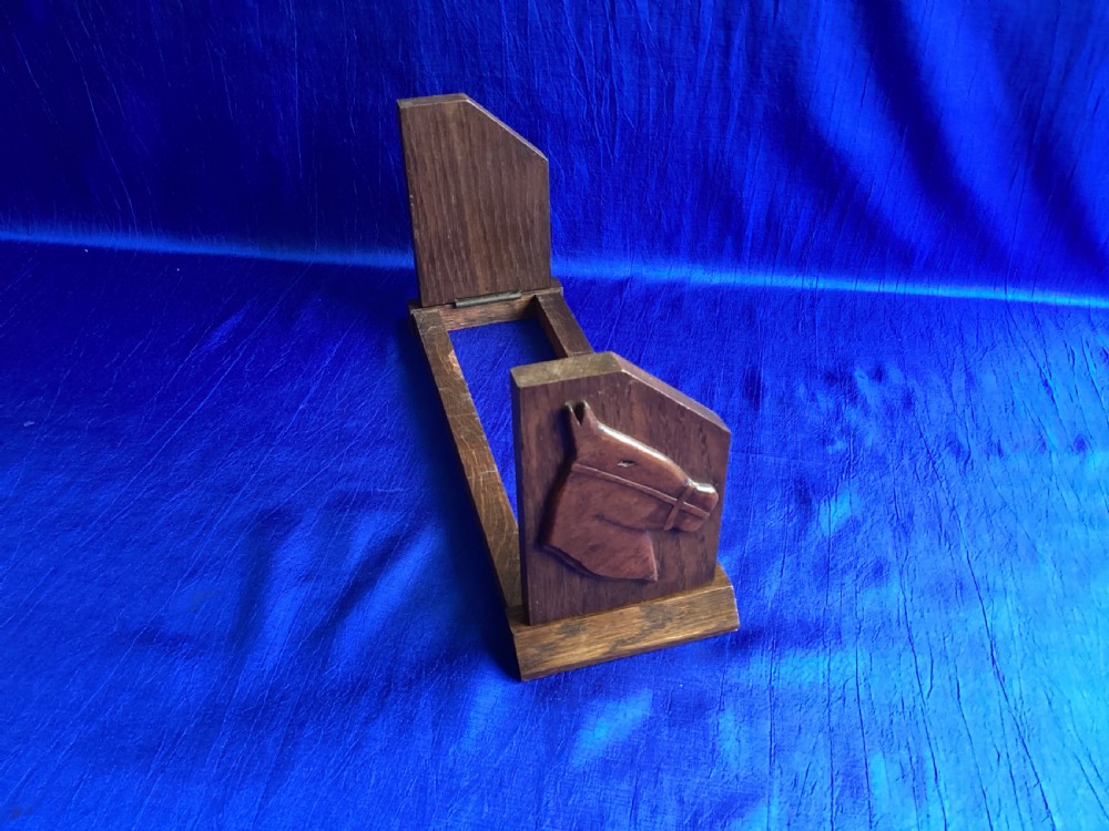A solid oak Art Deco desktop book trough featuring angled side supports with carved horse silhouettes connected by twin horizontal rails. View V
