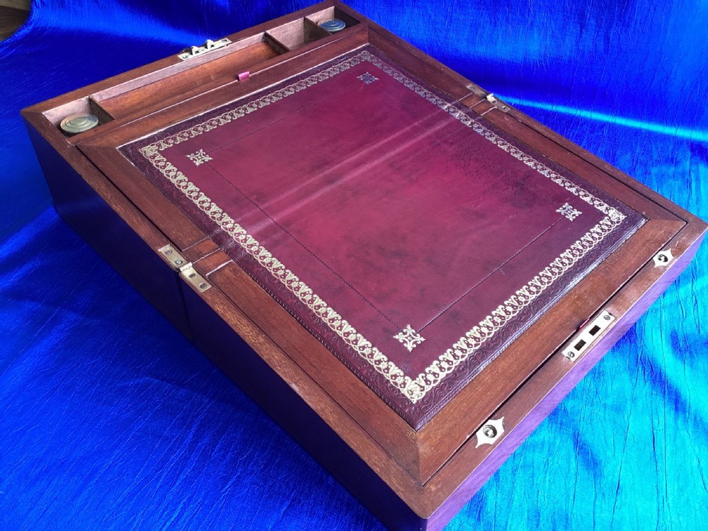 A rectangular dark walnut wooden writing slope featuring stylised floral marquetry inlay across the top lid and a key with a pink tassel in the front lock. View VII