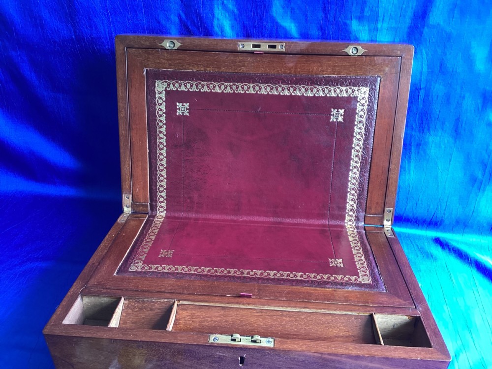 A rectangular dark walnut wooden writing slope featuring stylised floral marquetry inlay across the top lid and a key with a pink tassel in the front lock. View IX