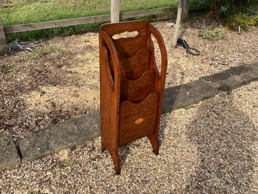 A floor-standing Edwardian oak magazine rack featuring three tiered sections, an integrated top handle aperture, and an oval marquetry shell inlay on the lower panel. View II