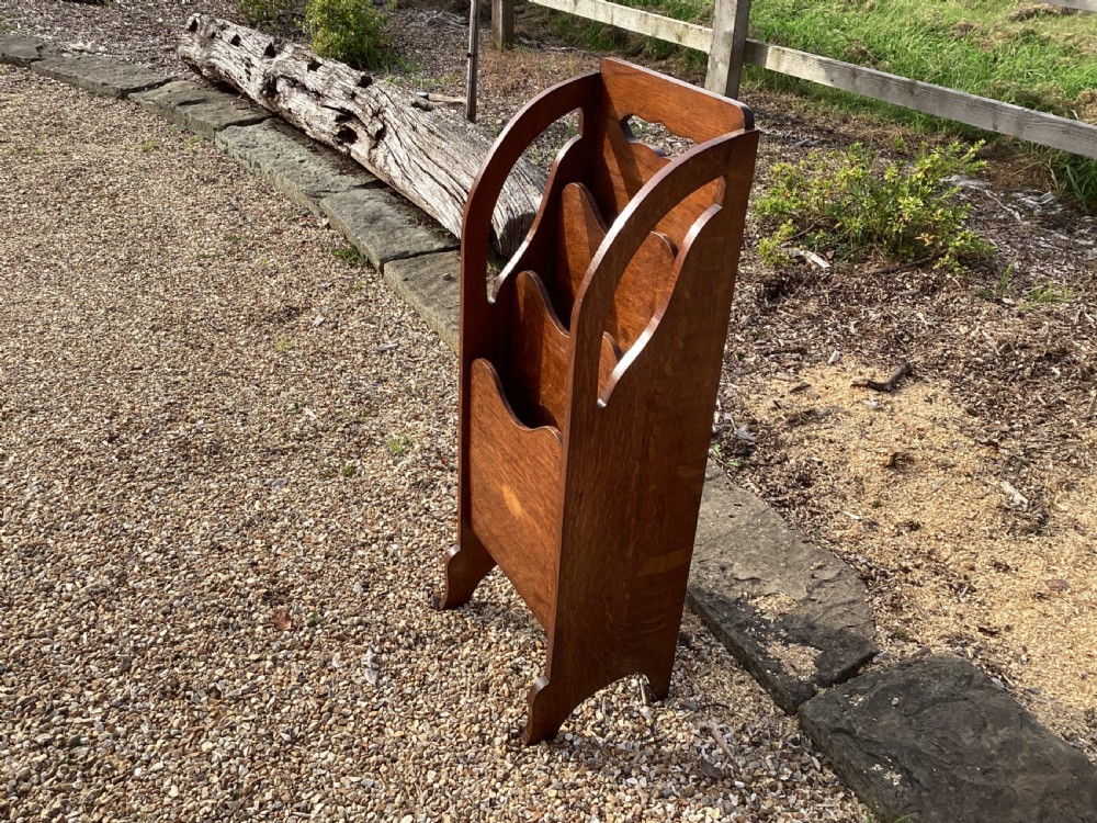 A floor-standing Edwardian oak magazine rack featuring three tiered sections, an integrated top handle aperture, and an oval marquetry shell inlay on the lower panel. View IV