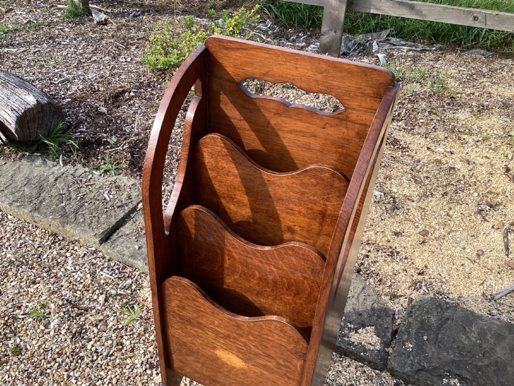 A floor-standing Edwardian oak magazine rack featuring three tiered sections, an integrated top handle aperture, and an oval marquetry shell inlay on the lower panel. View VI