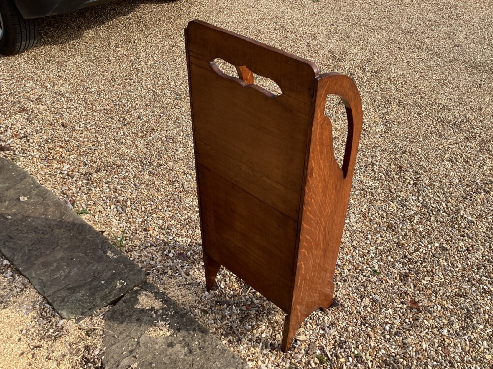 A floor-standing Edwardian oak magazine rack featuring three tiered sections, an integrated top handle aperture, and an oval marquetry shell inlay on the lower panel. View VIII